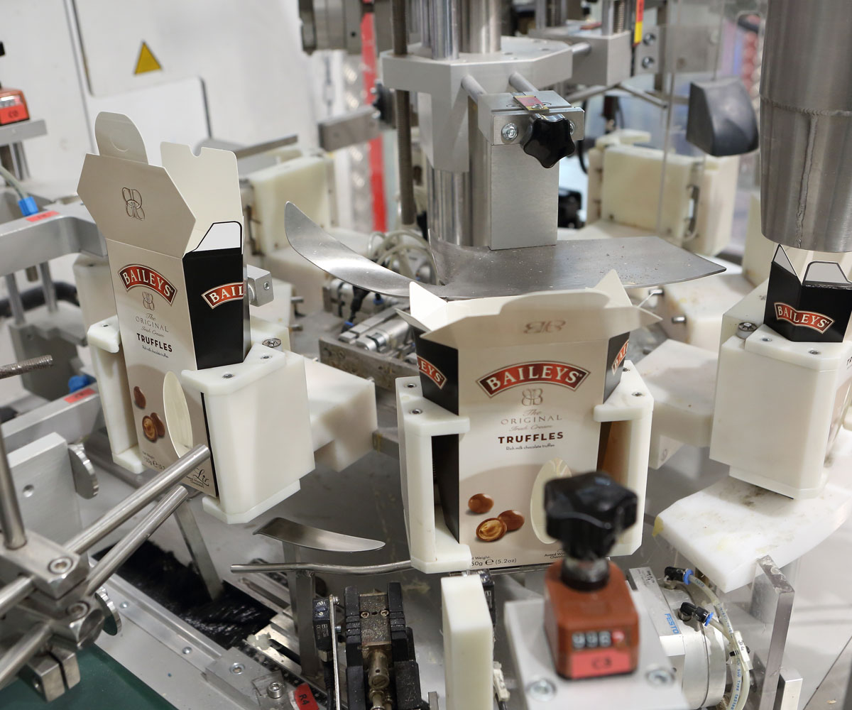 Photo of an automated cartoning machine filling boxes of chocolate liqueurs