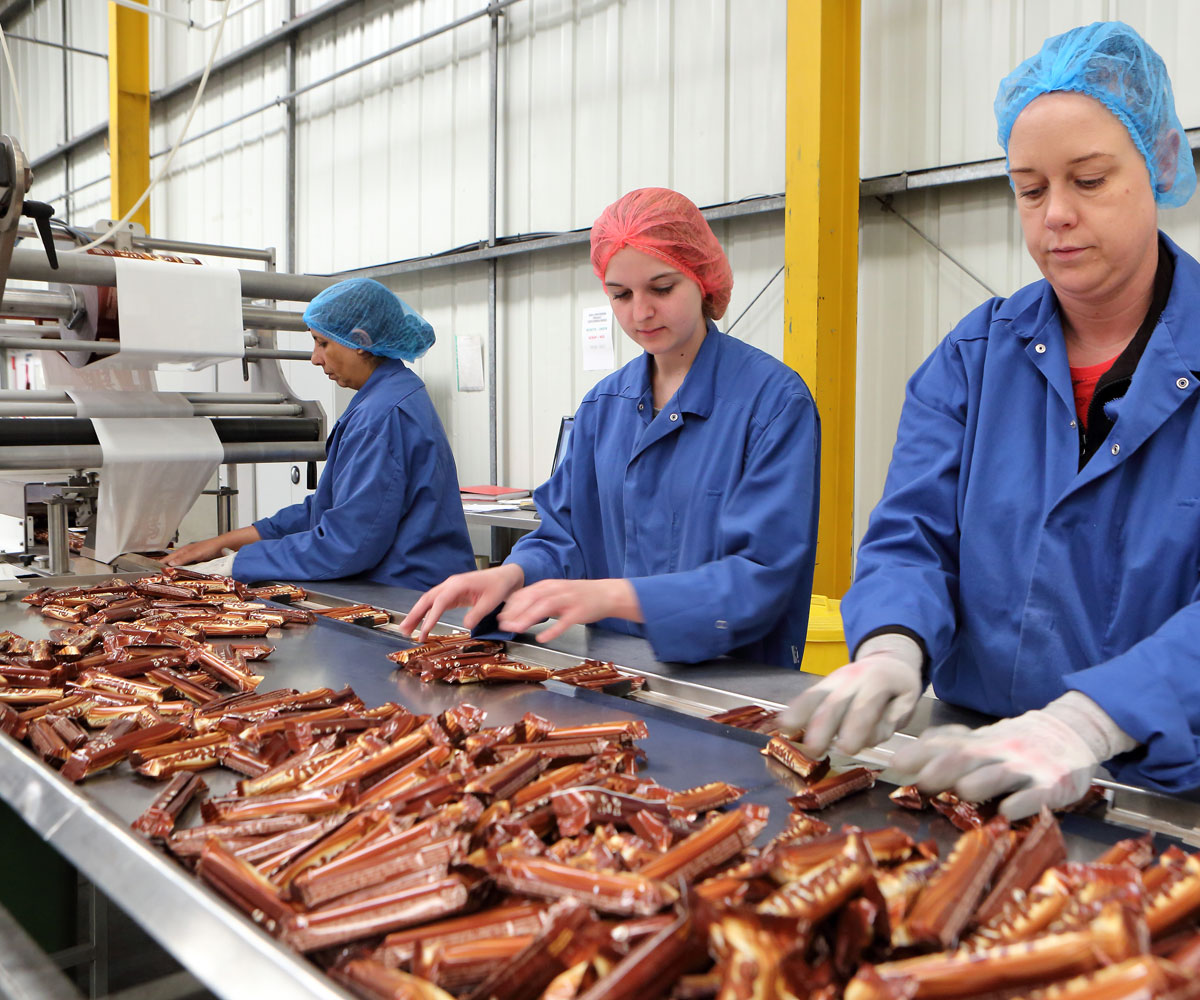 Photo of workers inspecting confectionery after flow-wrapping at SGL Co-packing factory